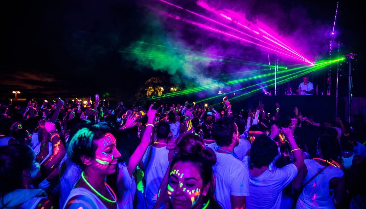 Tanzende Menge in fluoreszierender Körperbemalung unter UV-Licht und Lasern bei Festichola